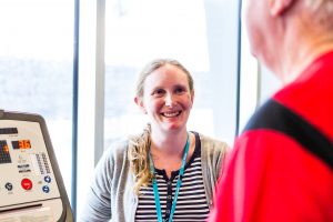 A woman wearing a Mercy Health lanyard smiles at a patient who is on a machine.